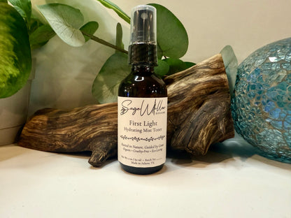 Bottle of 'First Light Hydrating Mist Toner' by Sage Willow on a surface with decorative elements.